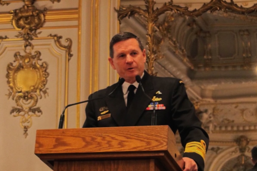 a defence chief wearing military uniform speaking at a lectern in a ballroom