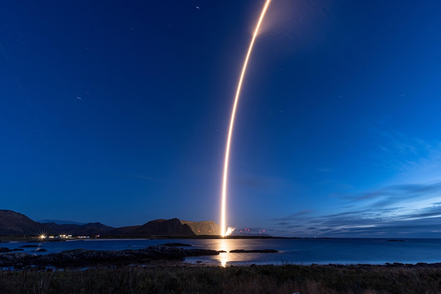 The flight path of a rocket illuminates a dark sky.
