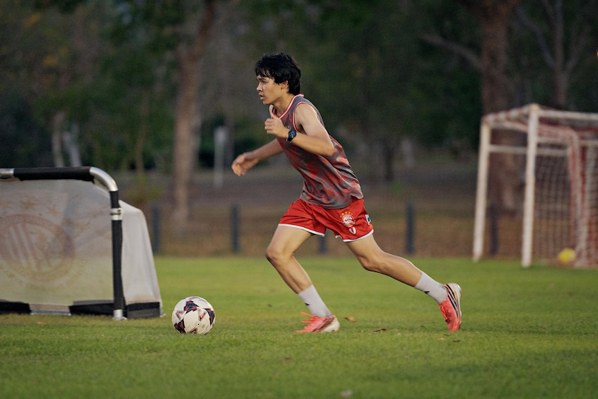 Mark O'Connor dribbles a soccer ball past a set of temporary goalposts.