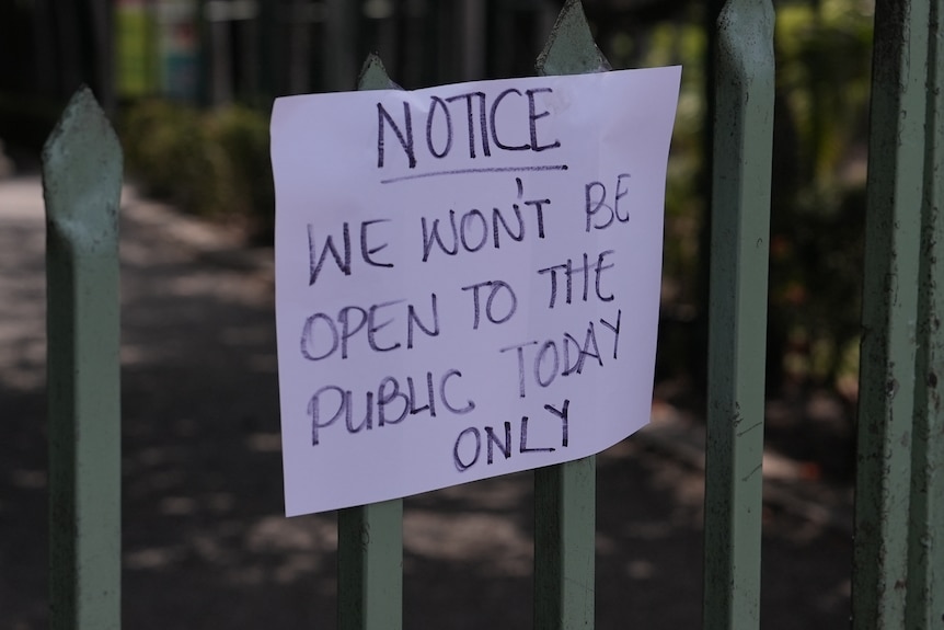 White sign on gate saying it is closed for the day.