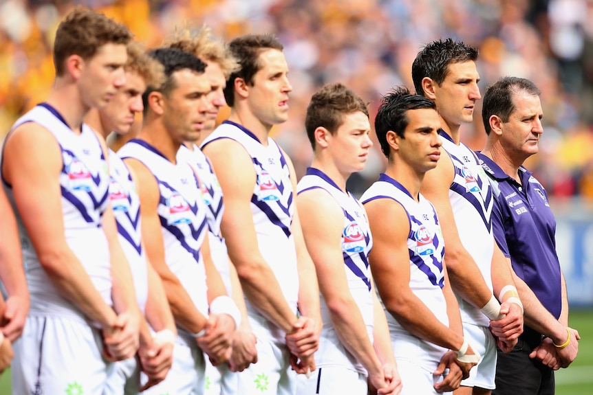 Lachie Neale standing next to Fremantle teammates and coach