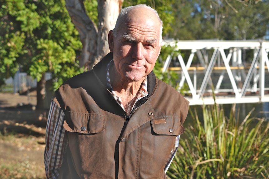 A man standing in front of a bridge by a lake