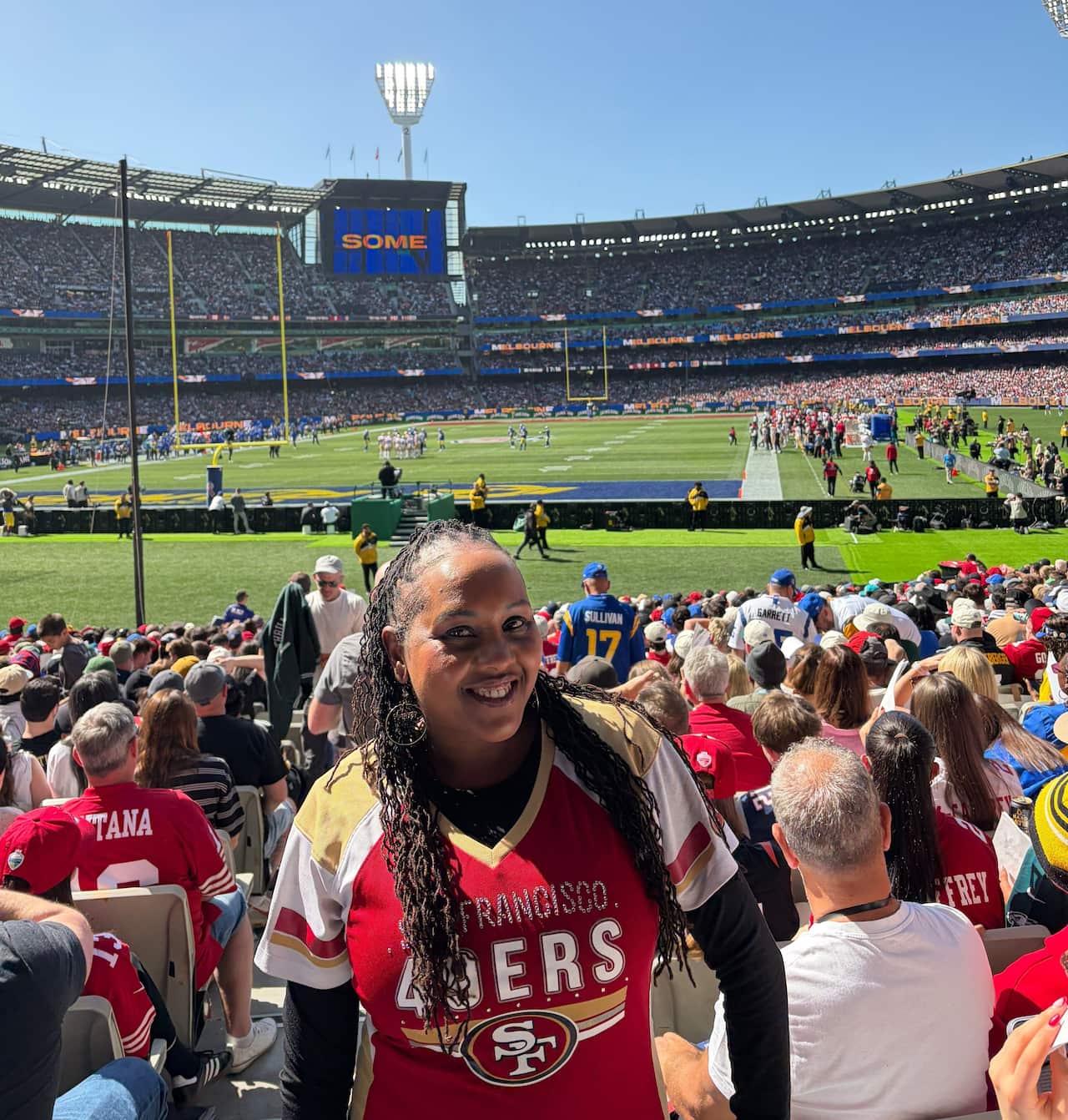 A woman wearing a San Francisco 49ers jersey poses at the Melbourne Cricket Ground stadium.