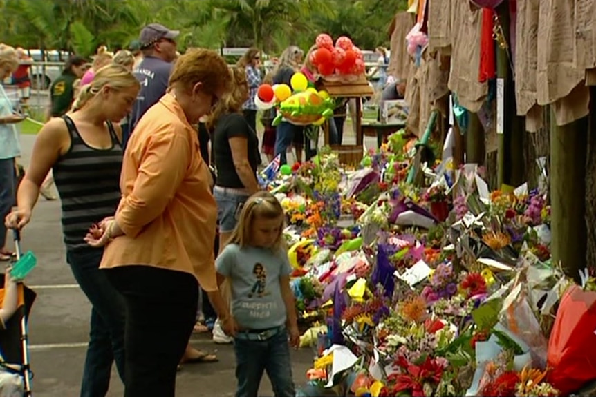 People standing outside zoo with flowers on ground