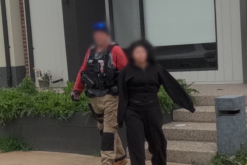 A hooded woman is arrested by police