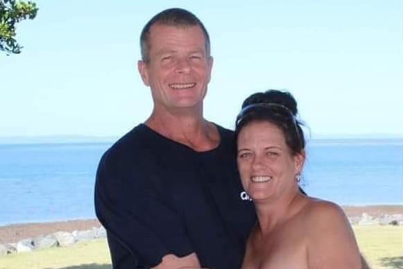 David Mobbs and Kylie Truswell-Mobbs stand arm in arm with the ocean in the background.