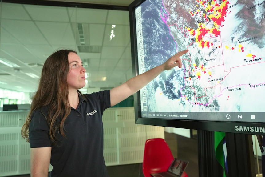 Grace Abbott points to a large screen showing the rain band.