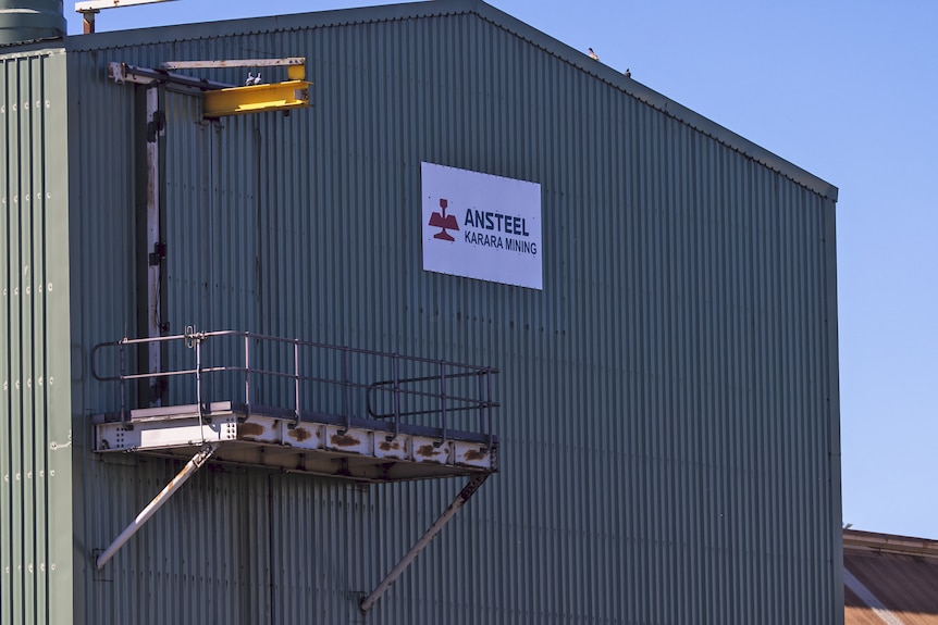 A large grey and green shed with a white sign and logo of Ansteel with text stating Karara