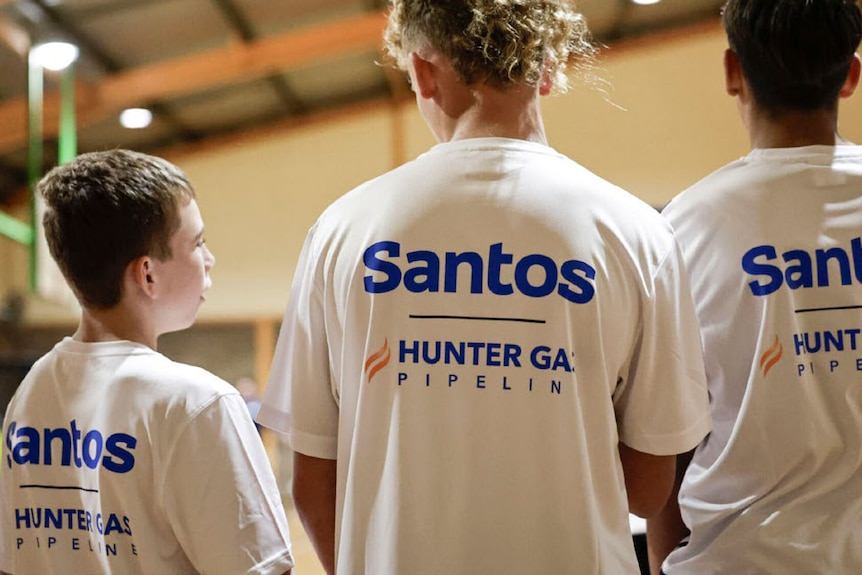 Three boys in Santos-branded T-shirts seen from behind.