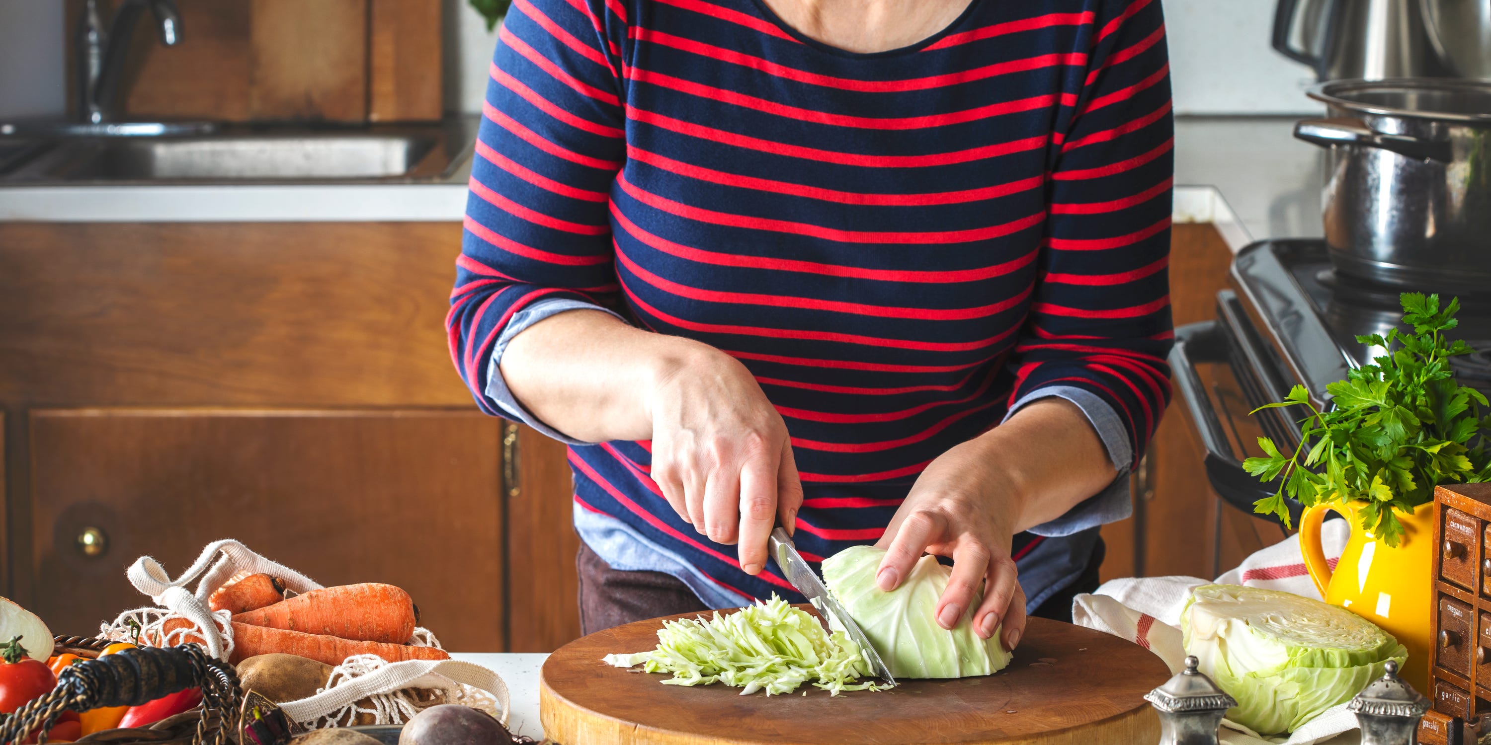 healthiest vegetables to eat - Woman cutting a green cabbage. Preparing food for cooking soup.