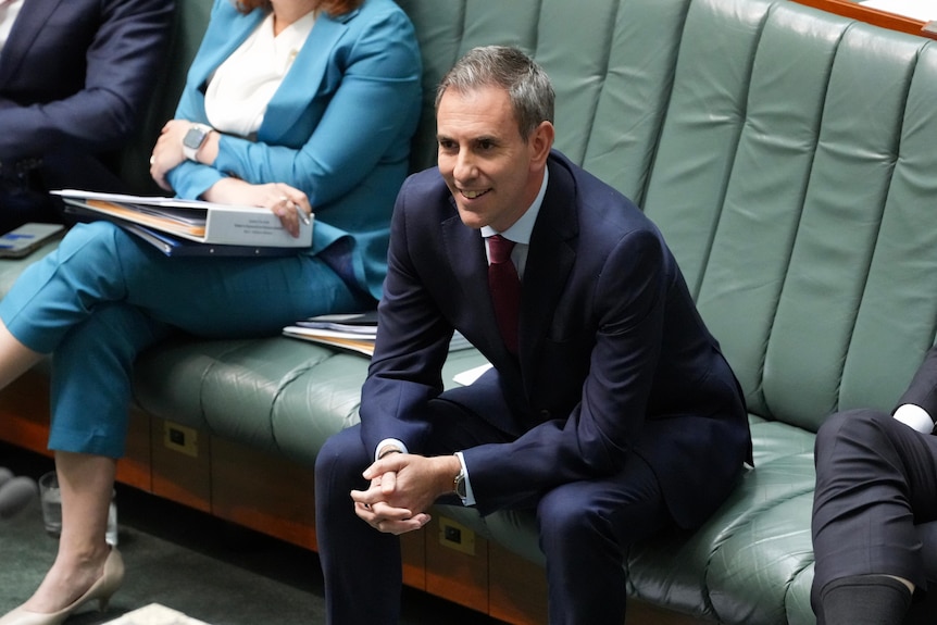 Jim Chalmers leans forward with his elbow on knees and hands clasped while sitting in the chamber.