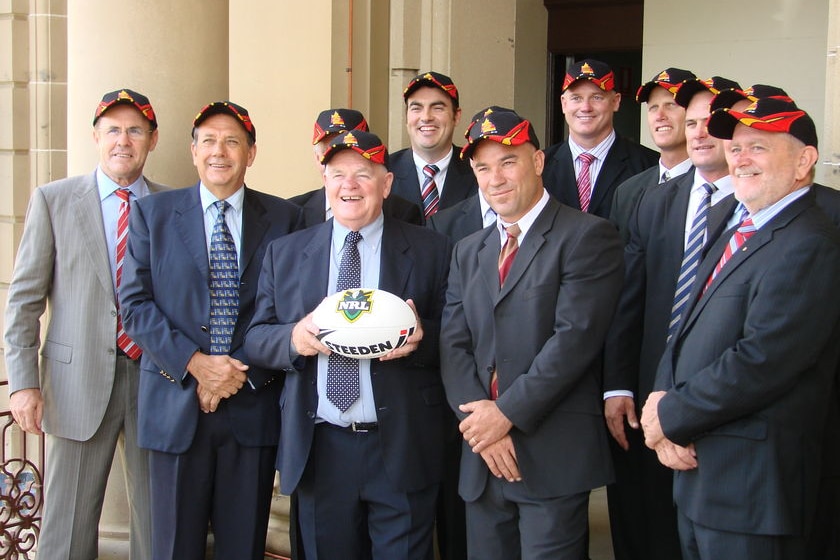A group of men in suit jackets holding a football