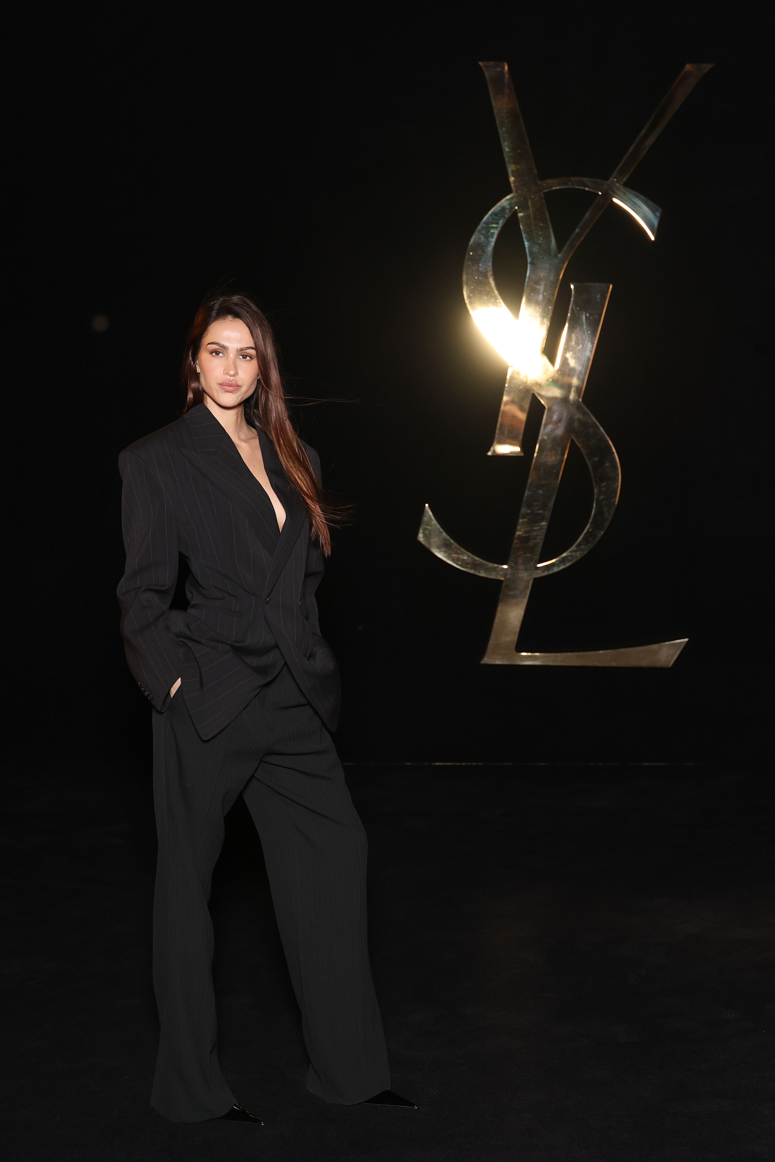 Amelia Gray Hamlin poses in a black pinstripe suit at the Saint Laurent show during Paris Fashion Week.