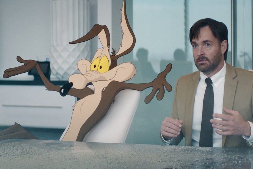 An animated coyote and a real-life person sit in a boardroom.