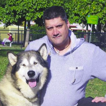 A man in a grey hoodie with a husky.