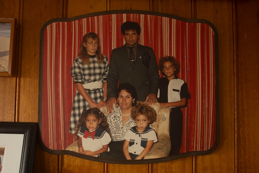 A photograph of a girl and boy sitting on a woman's lap, with Mr Cruse's dad behind the chair with an older boy and girl.