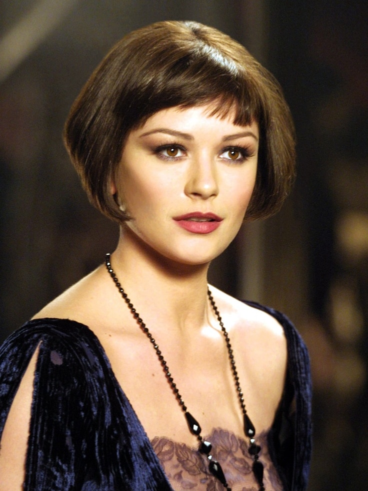 A close-up film still of Catherine Zeta-Jones, early 30s, with a bob haircut, in 20s-style dress, lips slightly parted.