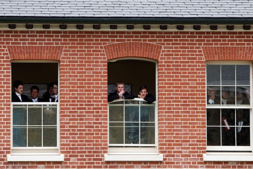 A crowd of students look through the windows.