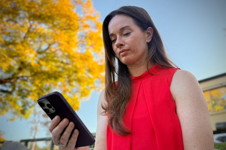A woman in a red sleeveless top looking at her phone