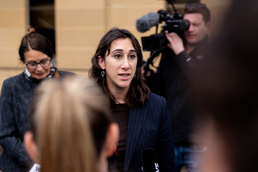 A woman speaks to the media outside a courtroom.