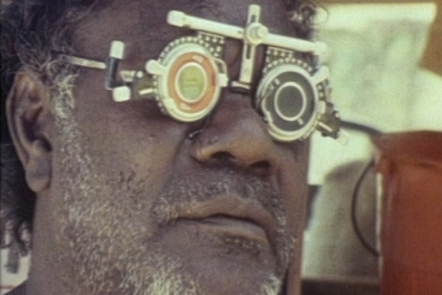 An Aboriginal man wearing eye-testing glasses used by optometrists.