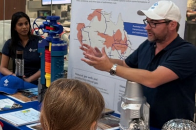 A man stands in front of a map delivering a presentation to school kids.