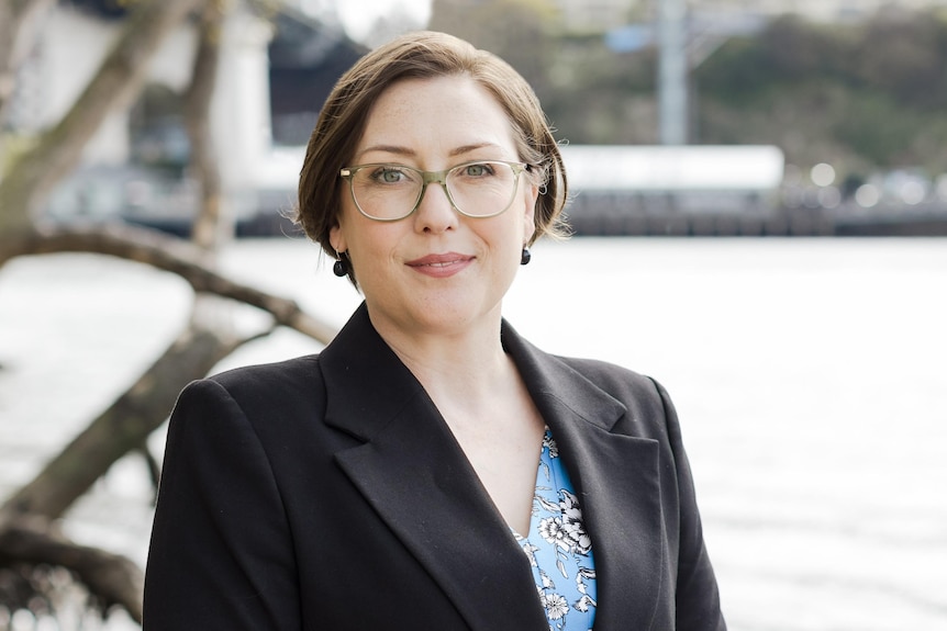 female looking at the camera wearing glasses in a suit