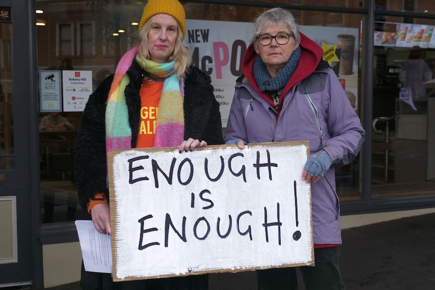 two women holding signs somberly