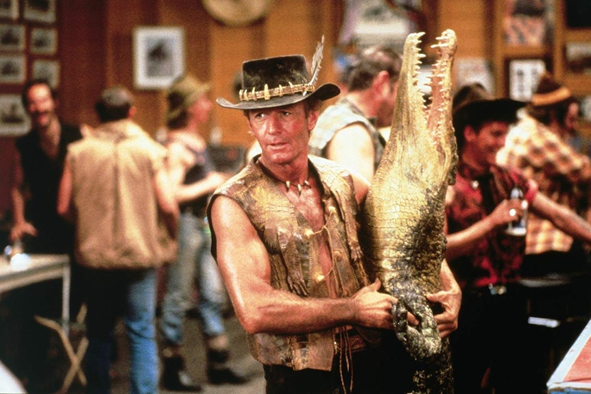 A still of Paul Hogan holding a crocodile from the 1986 film Crocodile Dundee.
