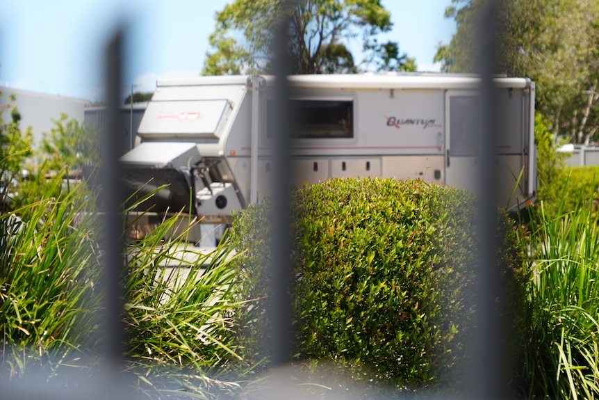 long shot of caravan, blurred fence in foreground