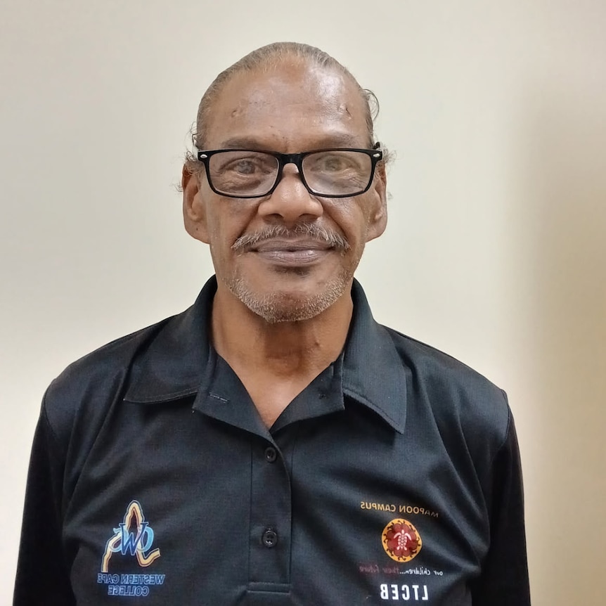 Ronaldo Guivarra has brown skin and facial hair, he is wearing black-rimmed reading glasses and looking at the camera.