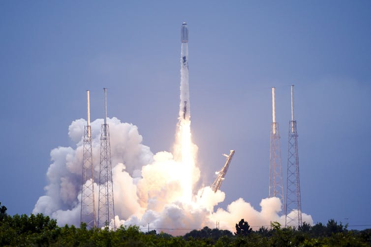 A rocket moving upwards off a launchpad, with a streak of flame and a plume of smoke coming off it.