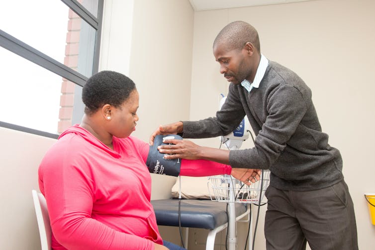 A woman in a pink hoodie having her blood pressure measured