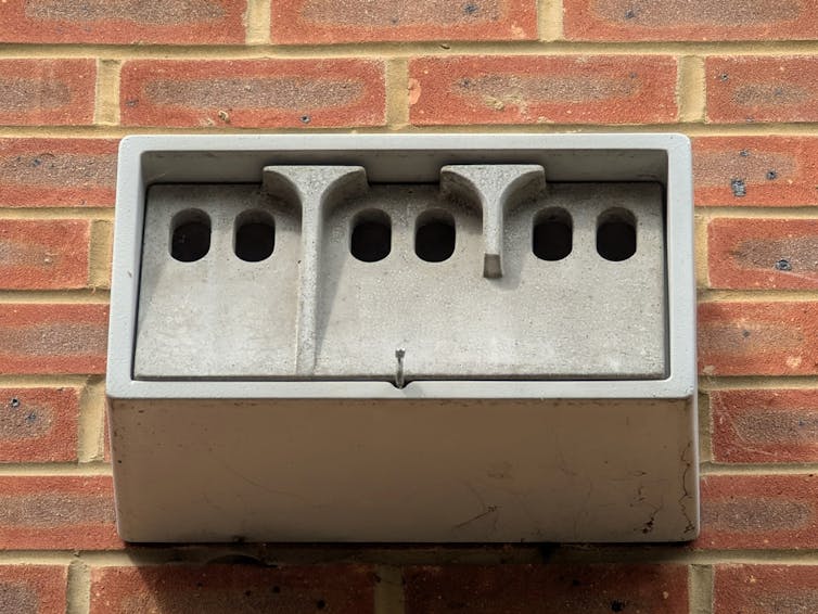 A concrete nesting box for birds, mounted on a brick wall.