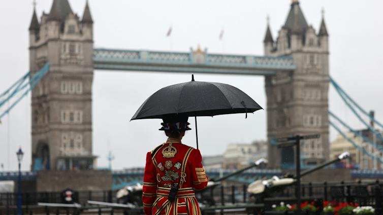 Beefeater under umbrella with Tower Bridge in background