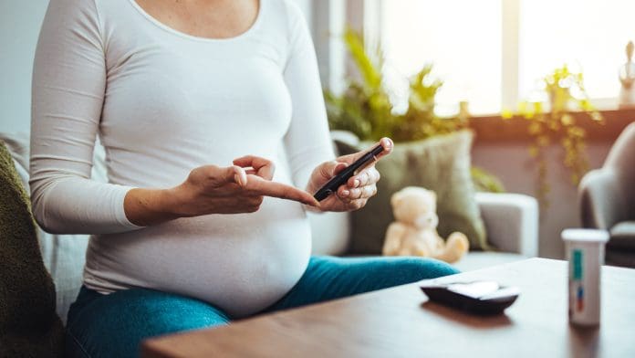A pregnant woman hands using lancet on finger to check blood sugar test level by Glucose meter