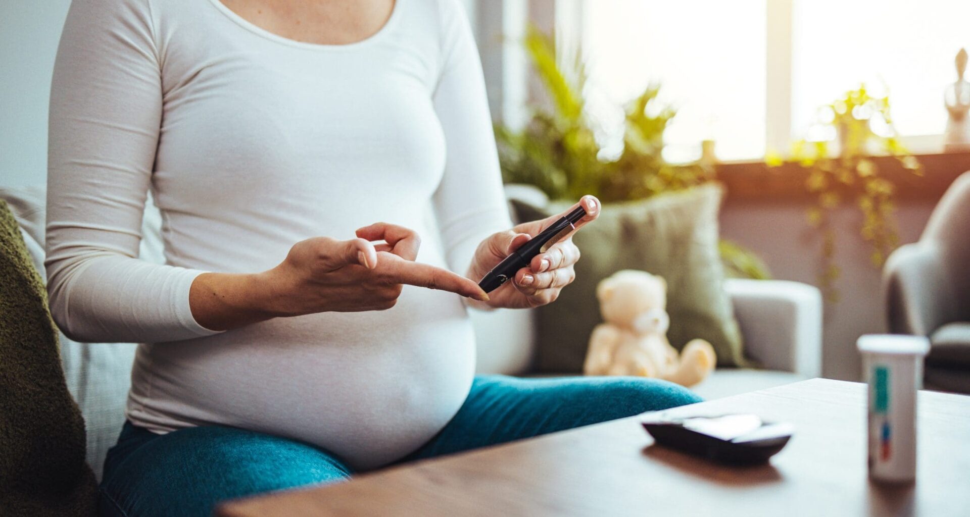 A pregnant woman hands using lancet on finger to check blood sugar test level by Glucose meter