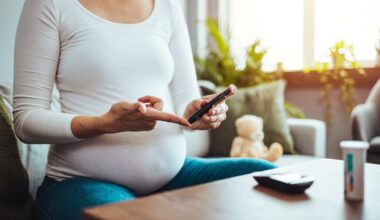 A pregnant woman hands using lancet on finger to check blood sugar test level by Glucose meter