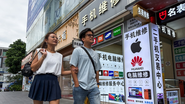 A mobile phone repair shop promoting support for Apple, Huawei, Samsung, Xiaomi, and Oppo devices in Shenzhen, China.