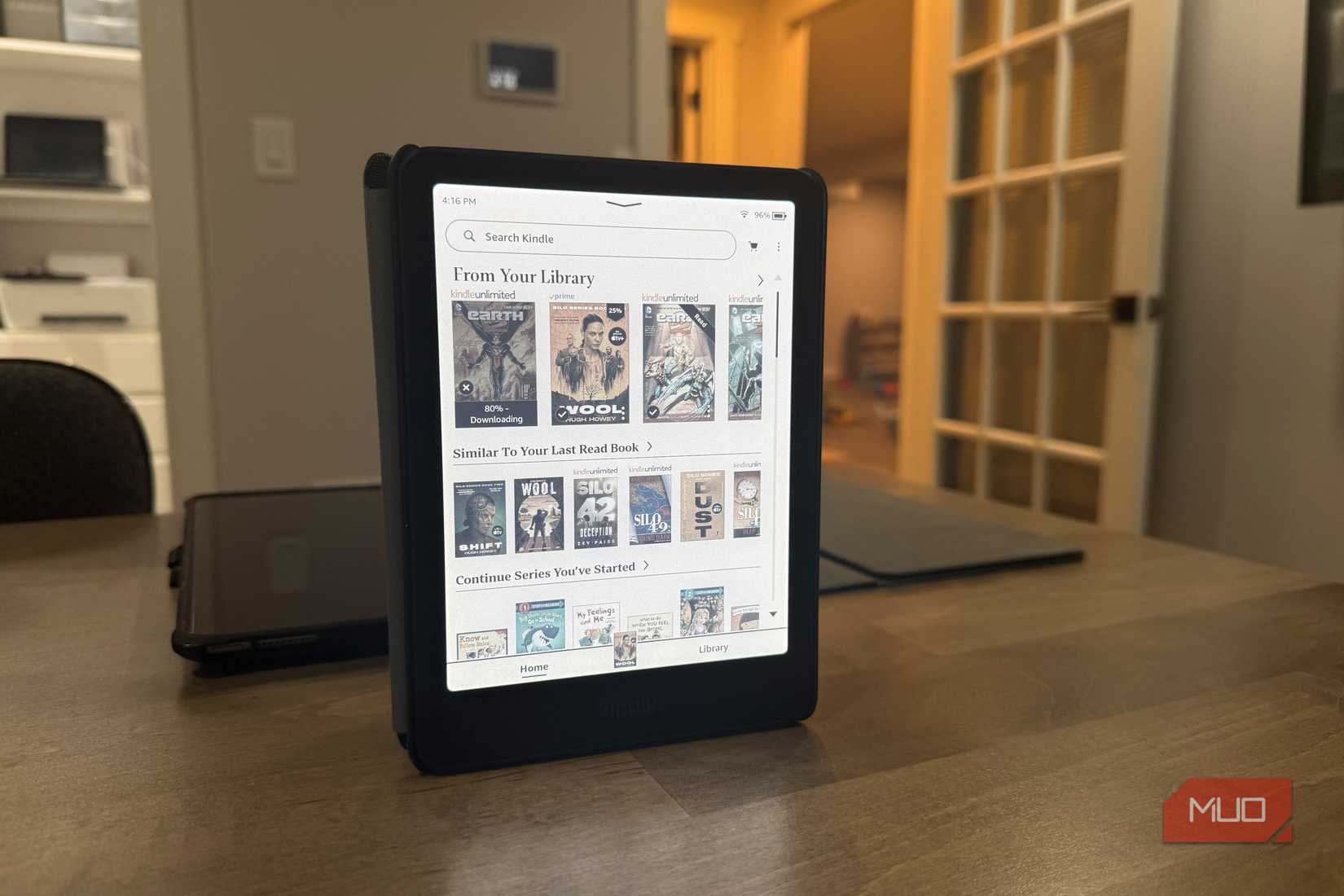Kindle Colorsoft on stand displaying library in office