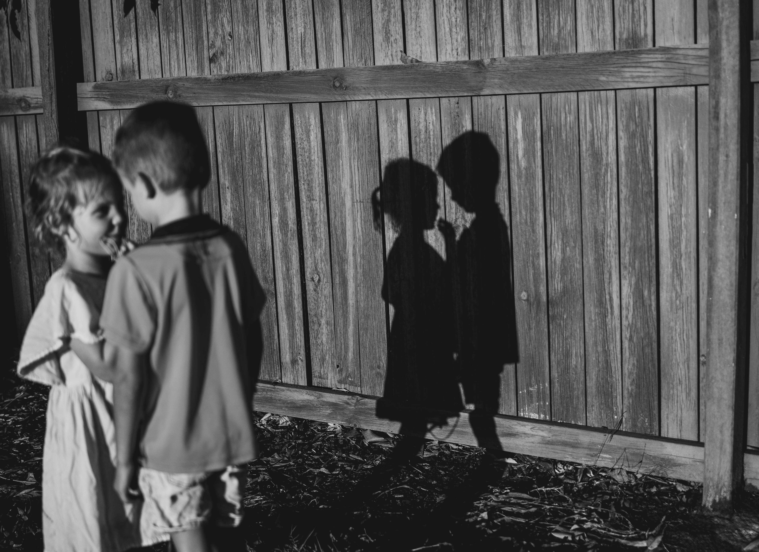 Shadow of two children on fence.