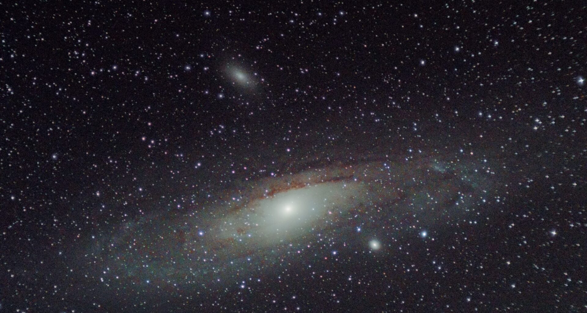 Andromeda is visible from 2.5 million light-years because the light of hundreds of billions of stars blends together. But an Earth-like planet there would be roughly ten billion times fainter than its own star and separated from it by only about 1.3 microarcseconds—far beyond the direct-imaging ability of any existing telescope.