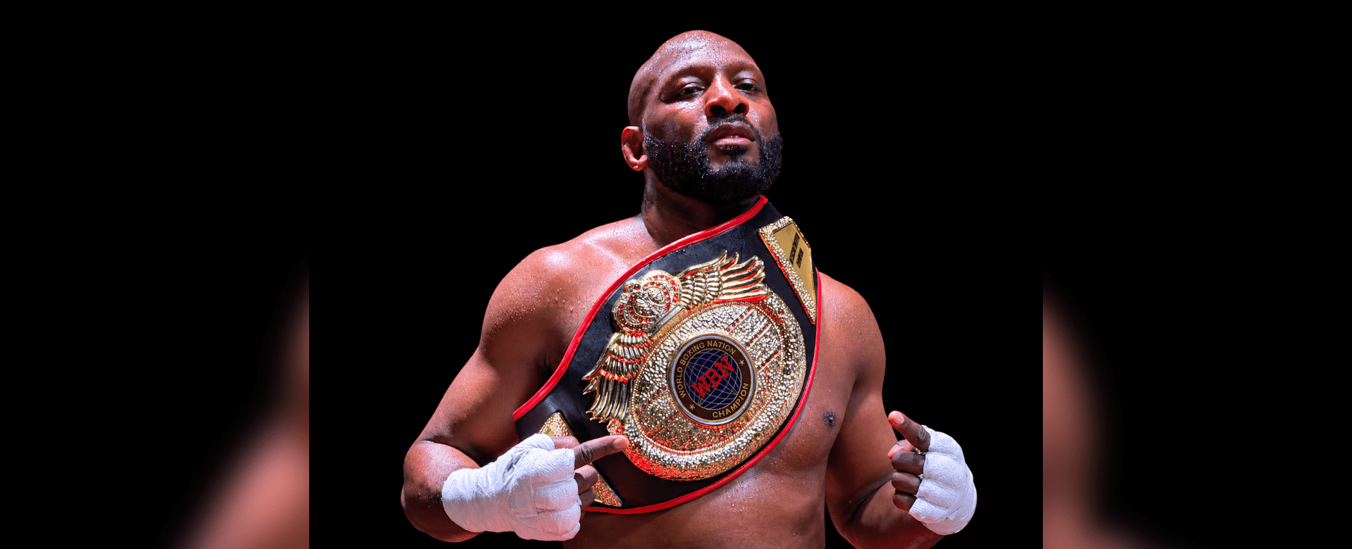 Martin Trey Brown, a muscular fighter, poses confidently with a championship belt in a boxing ring, showcasing his MMA suc…