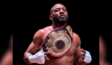 Martin Trey Brown, a muscular fighter, poses confidently with a championship belt in a boxing ring, showcasing his MMA suc…