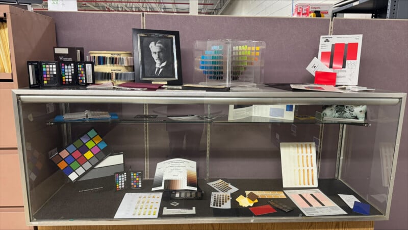 A display case filled with various color calibration charts, Pantone swatches, and a framed portrait of Albert H. Munsell.