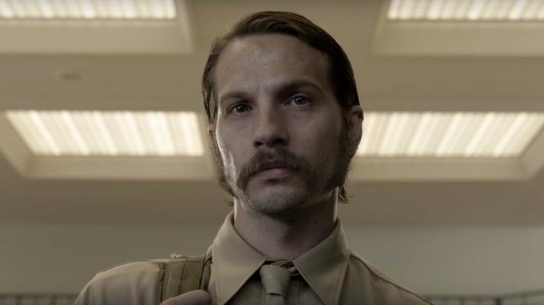 Mac Conway (Logan Marshall-Green) standing in a lit room on 