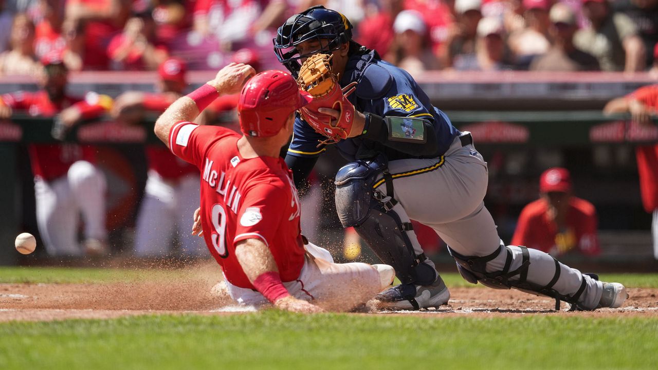 Cincinnati Reds' Matt McLain, left, scores as Milwaukee Brewers catcher Bo Naylor bobbles the throw to home plate in the second inning of a baseball game, Sunday, Sept. 6, 2026, in Cincinnati. (AP Photo/Kareem Elgazzar)