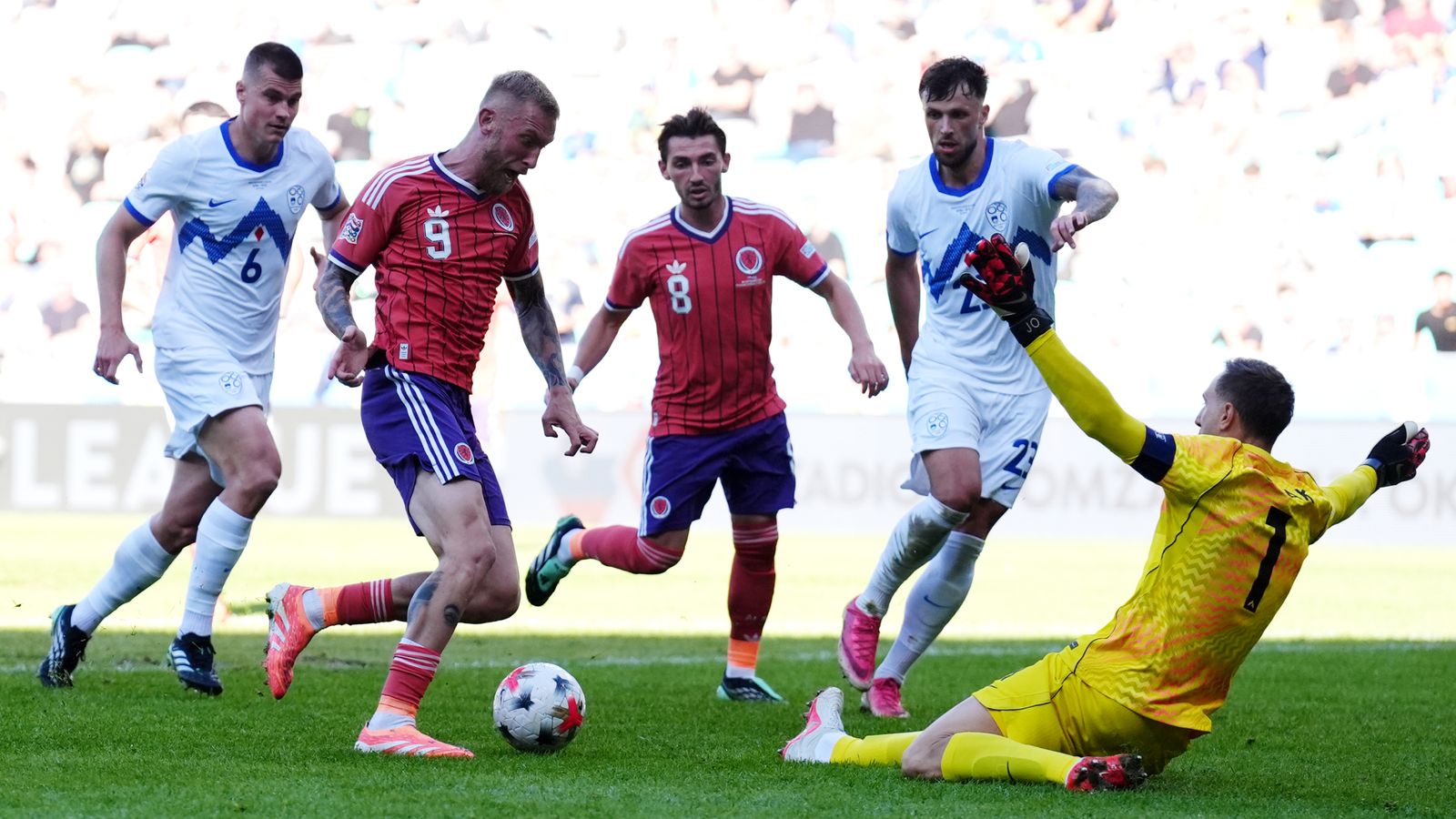 Slovenia goalkeeper Jan Oblak saves at the feet of Scotland's Oli McBurnie