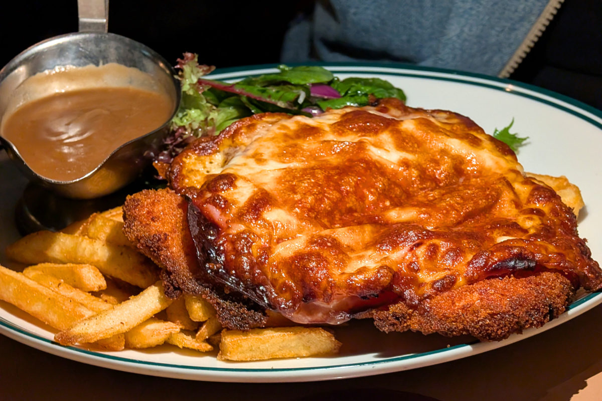 A plate with chips, salad and a golden parmi.