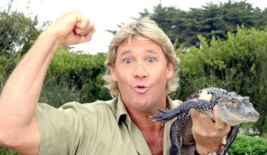 Steve Irwin holding a baby crocodile is his left hand, while raising his right hand in a fist